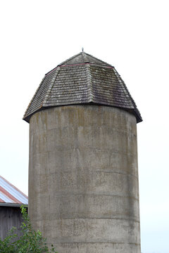 Old barn stone silo with wooden shingle roof isolated