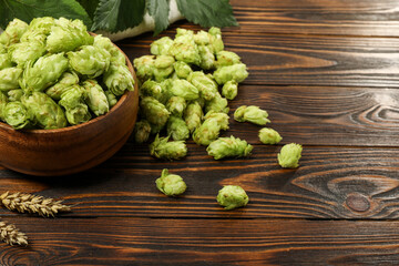 Fresh hop flowers and wheat ears on wooden table, space for text