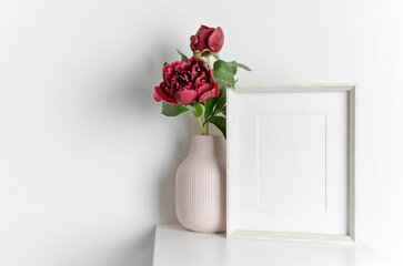 Frame mockup with fresh peony flowers in vase, blank mockup for artwork presentation