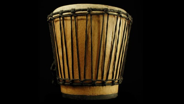 Isolated African Ethnic Musical Instrument Drum spins slowly on turntable against black background