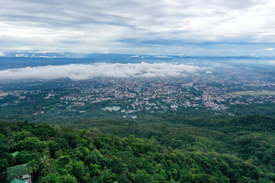 Top view of mountain in Chiang Mai City, Thailand. White cloud and dust is above of the mountain while cities can be seen far away. © Surachetsh