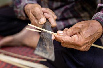 Fototapeta na wymiar Elderly, wicker, traditional handmade bamboo handicraft made old man hands and knife. Thailand