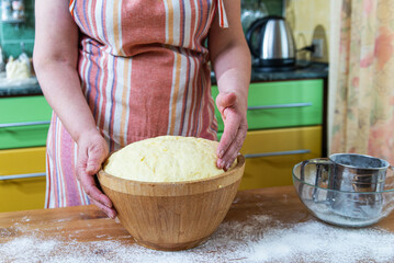 hostess prepares the dough. Dough that has doubled in size, dough that has risen, proofed dough in a wooden bowl