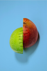Half red half green apple held together with stitches creative still life