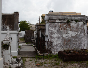 Fototapeta na wymiar Beautiful scene of St Louis cemetery No 1 in New Orleans Louisiana with gothic look and mausoleums. Plants growing on structures and paint chipping from brick work. 