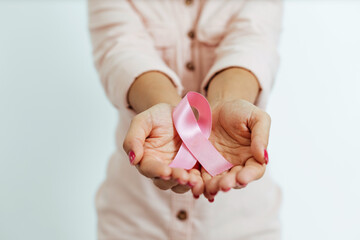 Close-up of woman's hands holding pink ribbon. Breast cancer awareness concept - obrazy, fototapety, plakaty