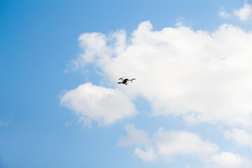 Defocus war drone. Drone flying in a blue sky. The black army unmanned aerial vehicle with four propellers and blades is on the blue sky background. Out of focus