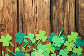 Flat lay composition with clover leaves and horseshoe on wooden background, space for text. St....