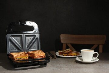 Modern grill maker with tasty sandwiches and cup of coffee on light grey table - obrazy, fototapety, plakaty