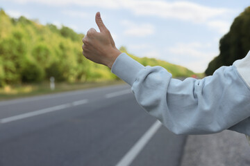 Woman catching car on road, closeup. Hitchhiking trip