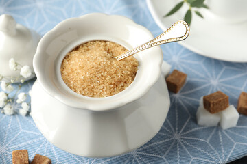Ceramic bowl with brown sugar and spoon on table