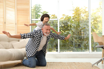 Happy grandfather with his grandson playing together at home