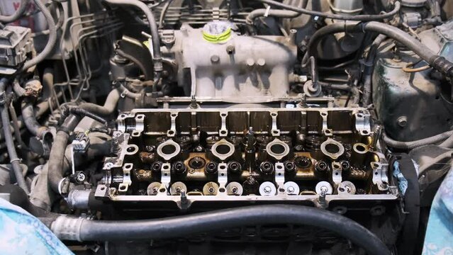 Disassembled car engine in oil. Cylinder head of an automobile engine. Refurbished car inside. Sixteen valves. Car service. Camera zoom
