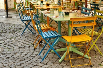 Deserted multicolored cafe seats and tables on sidewalk