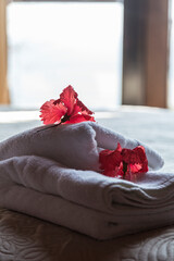 White towels and red flowers on the luxury hotel bed. Very cozy atmosphere. Vacation