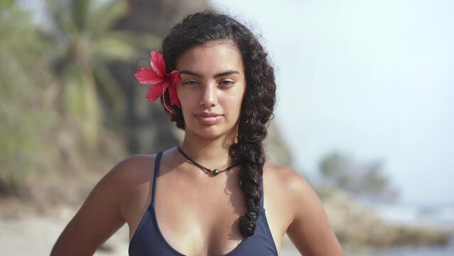 Young island woman with traditional hawaiian flower on tropical beach. Concept of paradise island, exotic vacation getaway, dream travel to Tahiti, French Polynesia.
