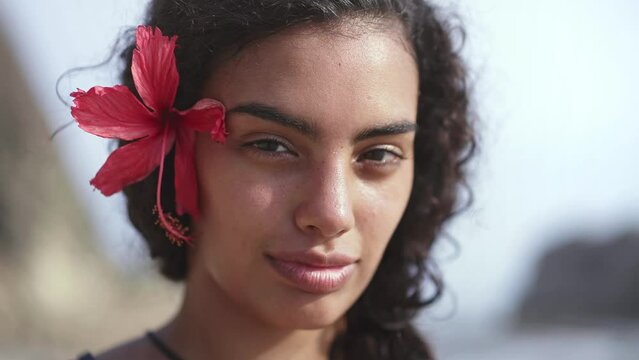 Young island woman with traditional hawaiian flower on tropical beach. Concept of paradise island, exotic vacation getaway, dream travel to Tahiti, French Polynesia.
