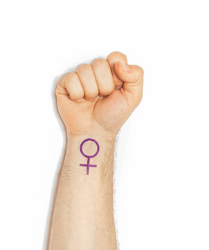 Raised Hand Making A Fist Gesture Of Power With A Feminist Feminism Logo Wrist Tattoo, Woman Power Concept Isolated On A White Background