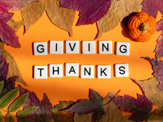 Thanksgiving flat lay composition. phrase Giving thanks in frame of autumn leaves and crocheted...