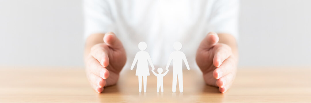 Hand Protecting Family On Wood Table. Healthcare And Life Insurance Concept