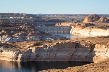 Fototapeta na wymiar Scenic View of a Serene Lake Powell and the Glen Canyon Dam With Rocky Cliffs During a Sunny Day