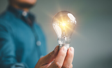 Idea innovation and inspiration concept. Hand of man holding illuminated light bulb, concept creativity with bulbs that shine glitter. Inspiration of ideas for sustainable business development...