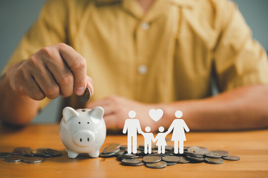 Businessman Putting Coin On The Piggybank And Icon Family On Table, Donation, Saving, Charity, Family Finance Plan Concept, Fundraising, Superannuation, Investment, Financial Crisis Concept...