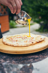 Ready hot pizza is poured sauce. The process of making homemade pizza. The concept of homemade fast food. Vertical photo.