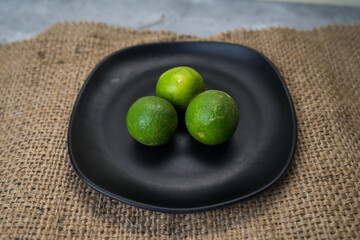 three limes on a black plate