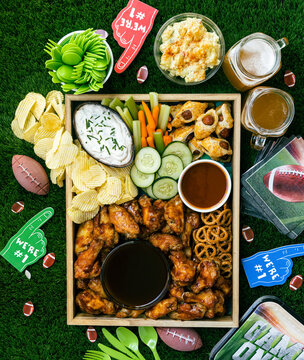 Looking down on a tray of healthy finger food, snacks, vegetables and drinks with football decorations for celebrating with friends and family on game day.