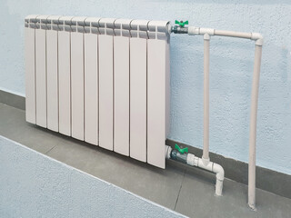 White modern aluminum radiator battery for hot water heating, on the background of a wall in the interior of an apartment or office space
