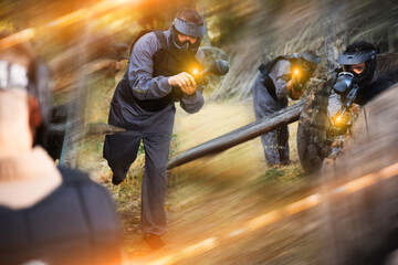 Man eliminating opponents on paintball field. Man in protective outwear and helmet targeting with paintball marker.