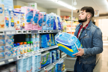 Fine father choosing disposable baby diapers in supermarket - obrazy, fototapety, plakaty