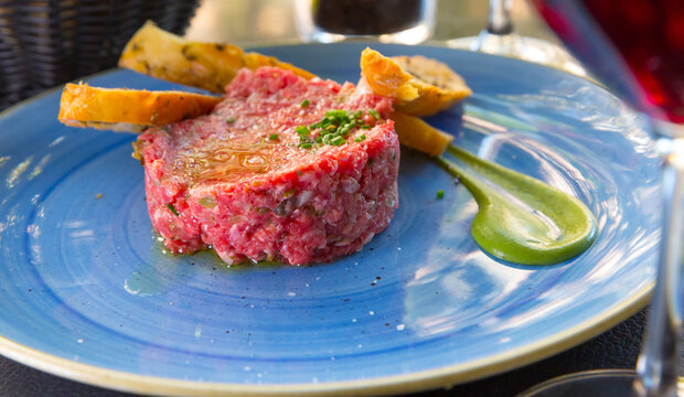 Image of delicious veal steak tartar served at plate with fried bread, food on cafe