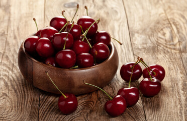 red ripe cherries in a wooden bowl on a building board
