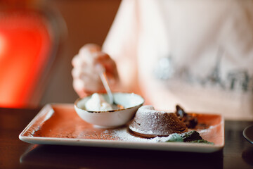 Young woman enjoying drinking cappuccino coffee and eating chocolate fondant cup indoor cafe. Tea...