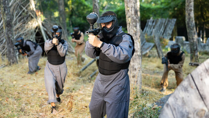 Fototapeta premium Man aiming with paintball market on battleground. Competitive shooting sport.