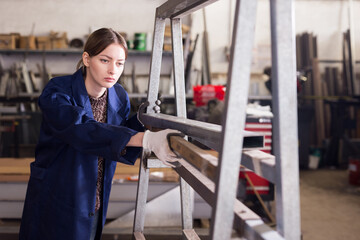 Fototapeta na wymiar Qualified focused workwoman inspecting shape of steel stocks in metal cutting workshop....