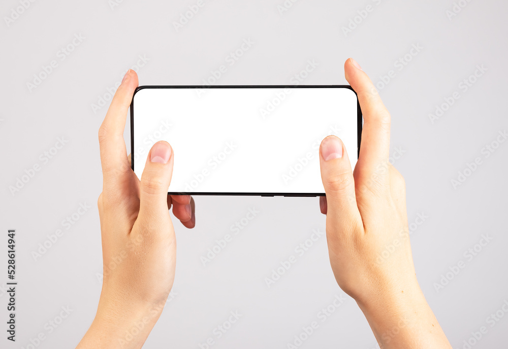 Poster Hands holding phone mockup in horizontal position. Woman using smartphone for playing games. Mobile gaming. template with blank display