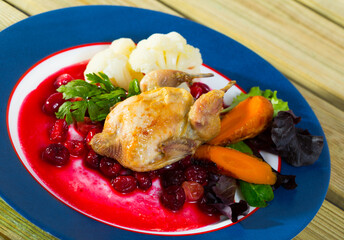 Delicious roasted ptarmigan with caramelized carrots, cranberries sauce, vegetables and greens