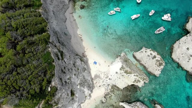 Drone footage from the Italian island of Tremiti shows the cliff's tree-lined edge, a white beach, and the gorgeous Adriatic Sea's crystal-clear seas, where boats are sailing 