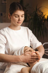 Beautiful Caucasian woman having spa massage of the head in beauty salon. Body care. Spa body...