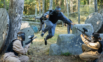 Tactical paintball players training on battlefield, charging opponent covers, jumping over...