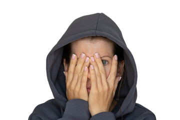 A girl in a tracksuit closes one eye with her hand on a white background, look through her hand