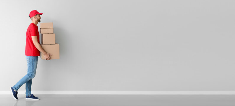 Delivery man with boxes on light background with space for text