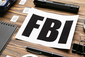 Paper sheet with abbreviation FBI and accessories of agent on wooden background