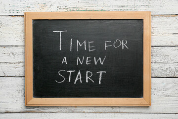Fototapeta premium Chalkboard with text TIME FOR A NEW START on white wooden background