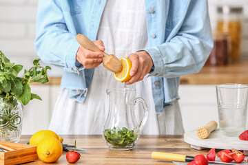 Woman squeezing lemon juice into pitcher in kitchen