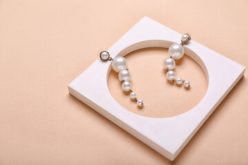 Fototapeta na wymiar Stylish pearl earrings on beige background