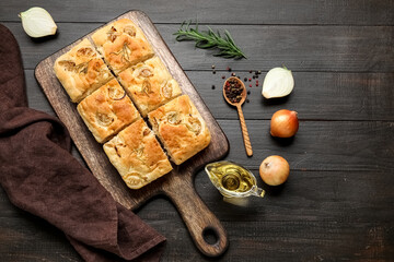 Composition with board of tasty Italian focaccia and ingredients on dark wooden background